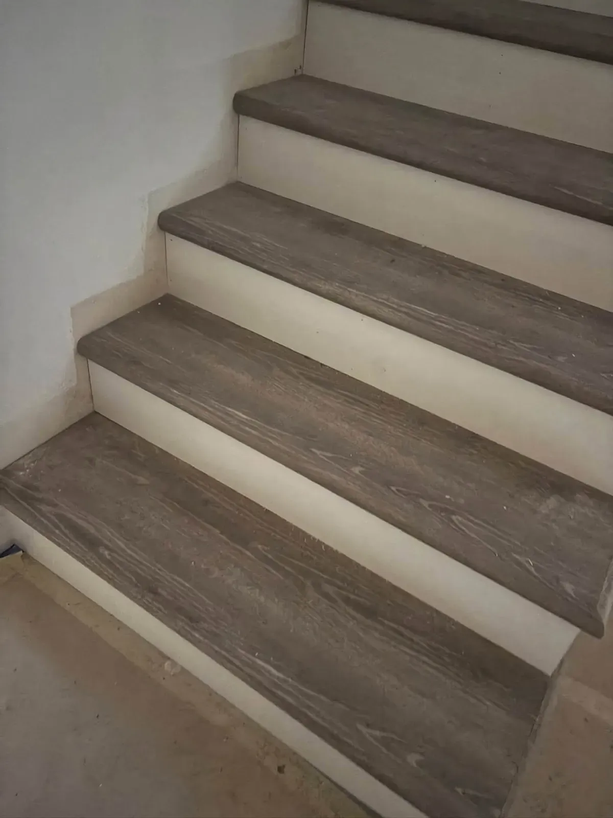 Stairs with new grey wood-look treads and white risers, photographed from the bottom step looking up.